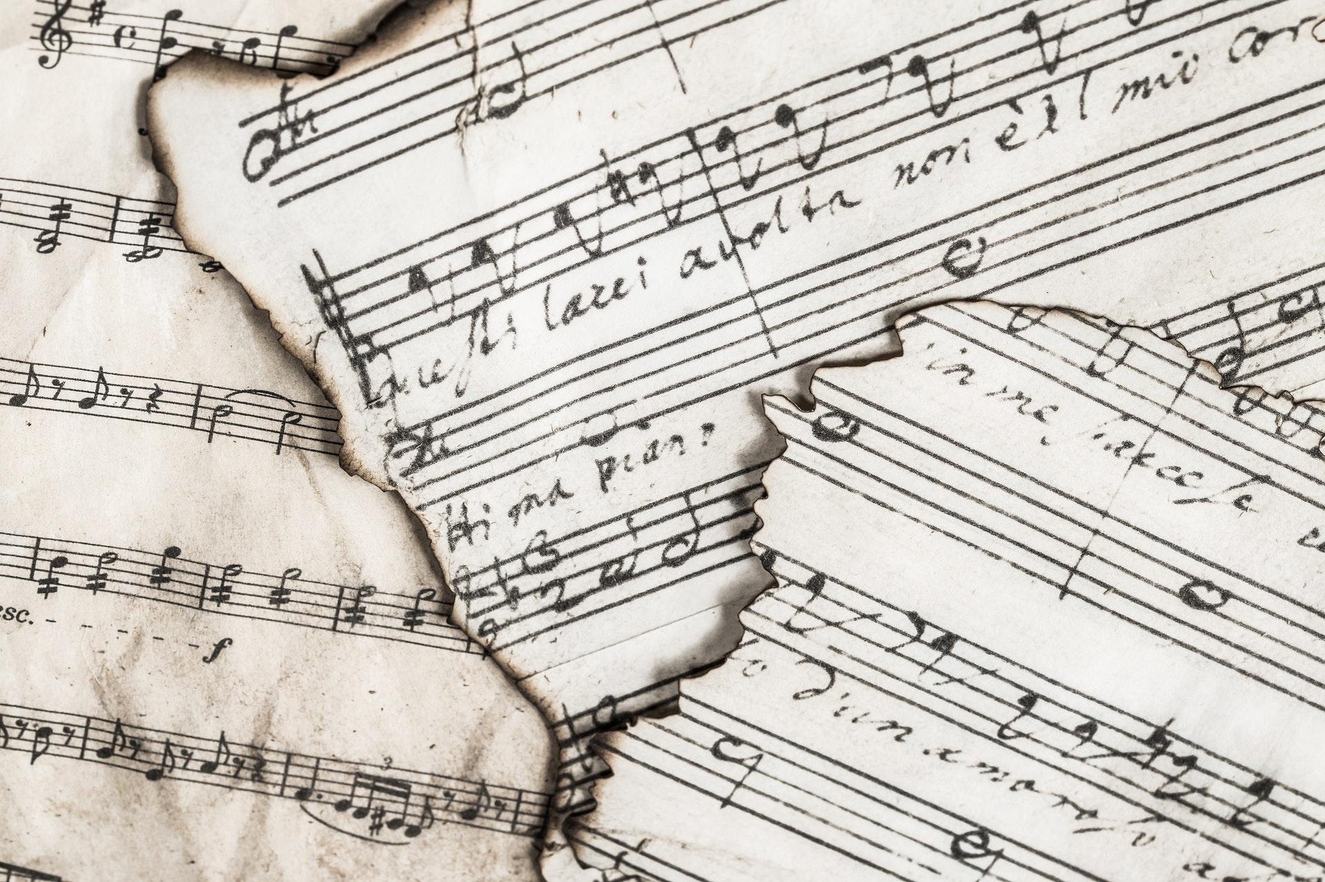 an image of three pieces of ripped sheet music on top one another